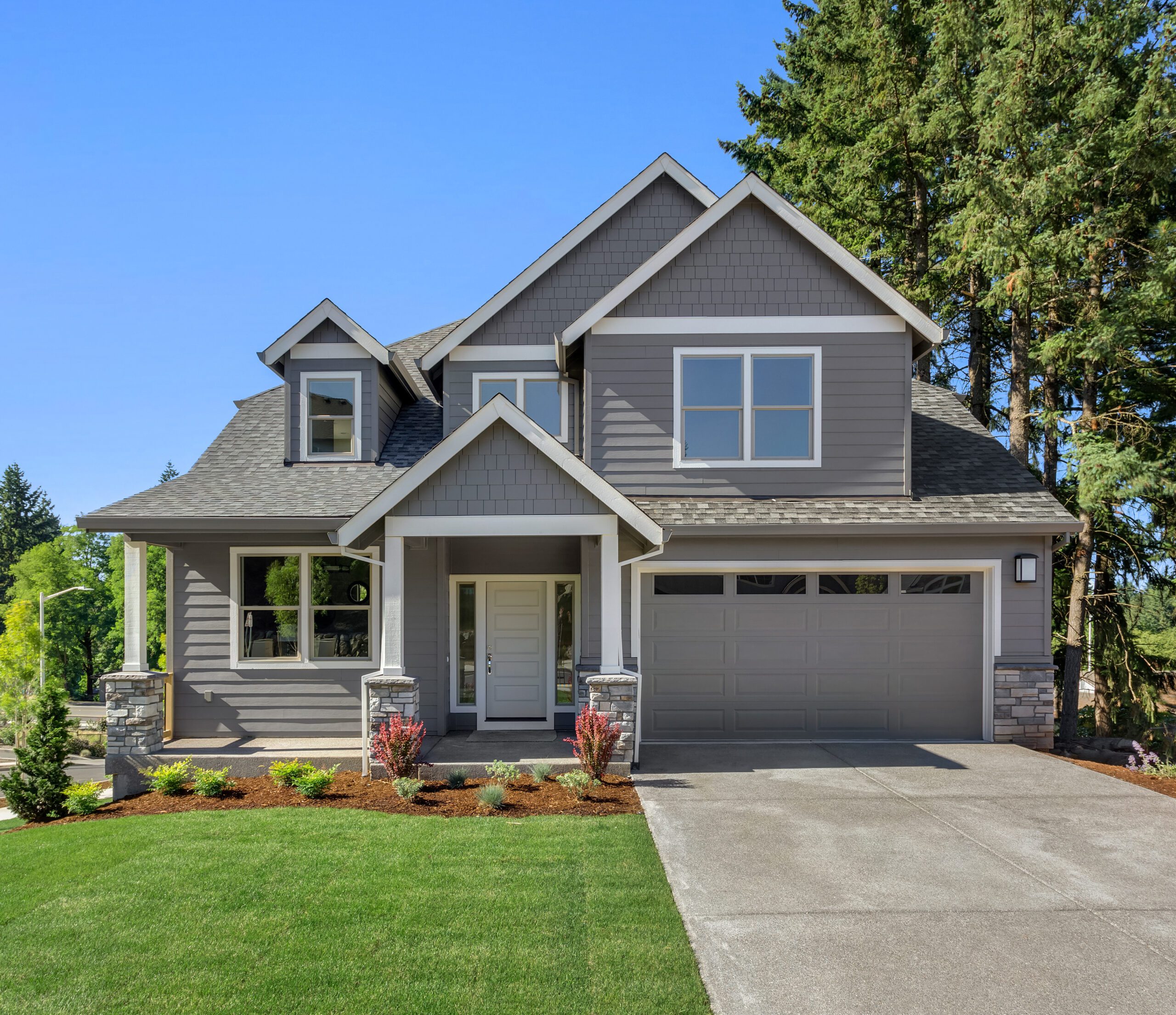 Suburban home exterior with new roof and new vinyl siding on bright sunny day, with large yard and covered porch